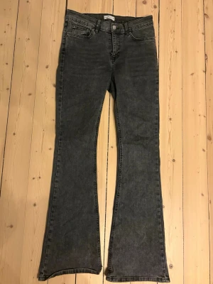 Grå bootcut jeans från Gina Tricot - Snygga grå bootcut jeans från Gina Tricot med klassisk femficksdesign och normal midja. Jeansen har utsvängda ben och är tillverkade i ett stretchigt denimtyg som sitter bekvämt. 