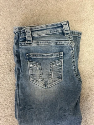 Lågmidjade utsvängda jeans med glitter bakfickor  - Ett par ljusblå jeans med glitter detalj på  bakfickorna, bootcot lågmidjade jeans från Gina  oanvända , hör av er vid intresse och fler bilder💕💕💕