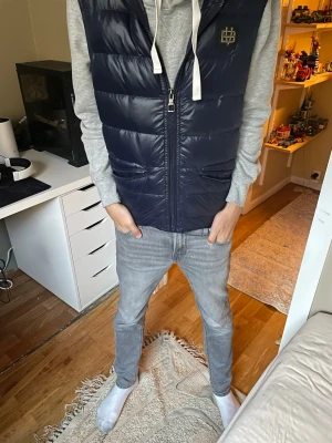 Mörkblå dunväst från Bvaldi - Tja! Säljer denna as feta  mörkblå dunvästen från Bvaldi med dragkedja och två fickor framtill. Den är som ny  ny endast använd en gång! Västen har en stor huva, samt ett diskret emblem på bröstet. Perfekt att slänga över en hoodie för en chill och trendig look. Tveka inte att ställa frågor vid minsta funderingar🙌