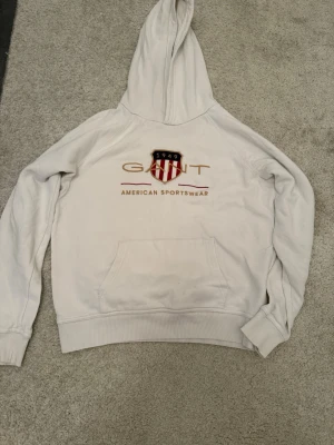 GANT Hoodie Shield Logo – Vit (Stl 176) - Gant hoodie Storlek: 176 cm / 16 år (Passar även XS/S) Skick: Mycket gott skick. 