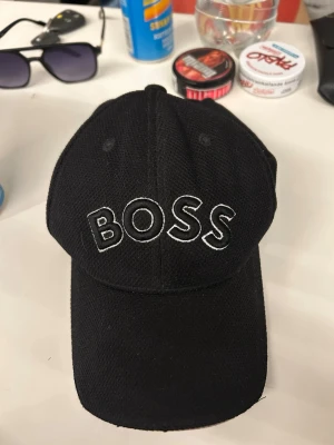 Svart keps med BOSS-brodyr - Snygg svart keps från BOSS inte använd mycket alls och har inga skador 