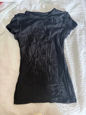 Svart kortärmad t-shirt XS - En enkel svart t-shirt i storlek XS med korta ärmar och rund hals. Perfekt basplagg till garderoben och lätt att matcha med olika stilar. Tillverkad i mjukt material som känns skönt mot huden.