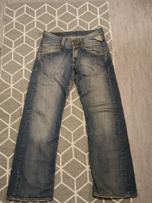 Replay jeans - Säljer ett par blåa jeans från Replay med raka ben och klassisk femficksmodell. Jeansen har slitningar och ljusare partier framtill för en cool, använd look. Materialet är denim i bomull och passformen är avslappnad. Perfekta till vardagsstilen!