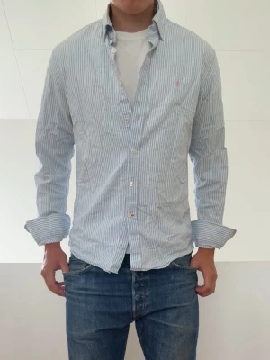 Ljusblå Randig Ralph Lauren skjorta - Ljusblå Randig Ralph Lauren skjorta sitter i strl S! Skjortan har lite slitage i kragen och har även liten missfärgning i armhålan men skulle säga inte något av d är något som märks av vid användning! Hör gärna av er vid frågor elr funderingar!!