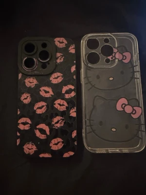 Två mobilskal med tryck - Säljer två mobilskal till iPhone. Ett svart skal med rosa kyssmunnar och ett genomskinligt skal med Hello Kitty-motiv och rosa/vit rosett. Båda skalen har öppningar för kamera och knappar. Perfekt för dig som vill ha ett personligt och lekfullt mobilskal.