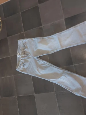Ljusgrå  jeans från Gina - Säljer ett par ljusgrå  jeans med klassisk femficksdesign och bälteshällor. Jeansen har dragkedjegylf och knapp framtill. Perfekta för en avslappnad och trendig look.Endast tvättade.