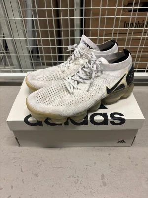 Nike Air VaporMax Flyknit 2 - Nike Air VaporMax Flyknit – White/Black – strl 44,5  Nike Air VaporMax Flyknit i vit/svart färgställning, storlek 44,5.  Begagnade med tydliga bruksspår. Ovandelen är i bra begagnat skick, men VaporMax-sulan har gulnat med tiden och plast/gummimaterialet har blivit hårdare. Detta är tydligt fotograferat och priset är satt därefter.  Säljs i befintligt skick. Perfekta för den som gillar äldre Nike/VaporMax-modeller.  Storlek: EU 44,5 Skick: Begagnat