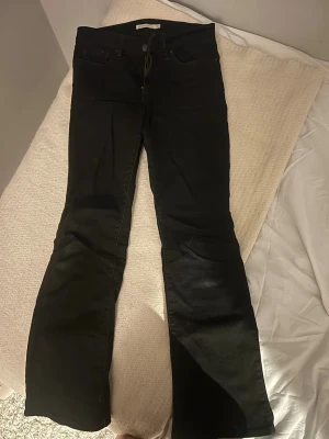Svarta bootcut jeans - Snygga svarta bootcut jeans med klassisk femficksdesign och utsvängda ben. Jeansen har låg midja och är tillverkade i ett stretchigt denimtyg som sitter bekvämt. Perfekta för dig som vill ha en tidlös och trendig look. De är lite slitna på insida lår möjligt ett litet hål men är lätt att sy annars tänker man inte på det💓