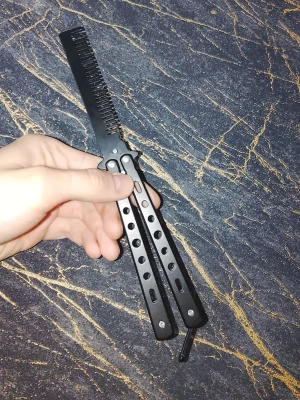 Butterfly training comb - Säljer en svart butterfly kam i metall med cool design. Perfekt för dig som vill styla håret med stil och samtidigt öva på butterfly-tricks. Bra kvalitet och smidig att trixa runt med.