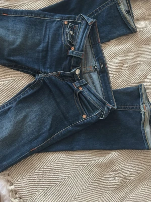 True religion jeans - Väldigt snygga jeans i ett tåligt material, köptes för ett år sen ungefär! Har såklart lite slitningar längst ner vid benen som man ser på bild 1, men det är inget man tänker på! Innerbenslängden är 78 ungefär och midjemåttet är 38!