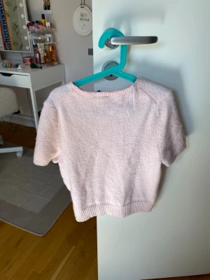 Ljusrosa kortärmad topp från H&M - Mysig ljusrosa topp från H&M i storlek XS. Toppen har korta ärmar, rund halsringning och är gjord i ett mjukt, fluffigt material. Perfekt för dig som gillar en söt och enkel stil.