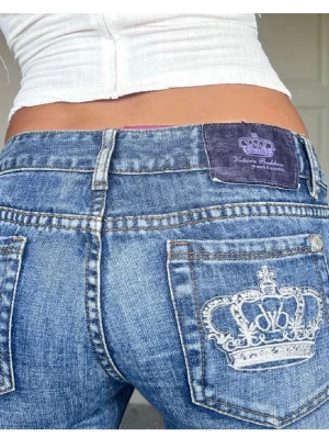 Blå bootcut jeans med kronbrodyr  - Snygga blå bootcut jeans från Victoria Beckham med låg midja och broderad krona på bakfickan. Jeansen har klassisk femficksdesign, slitna detaljer och en mörkblå patch med logga bak i midjan. Dom är helt nya dom passade inte mig i längden då jag är 176 . Skriv gärna om du är intresserad och om pris