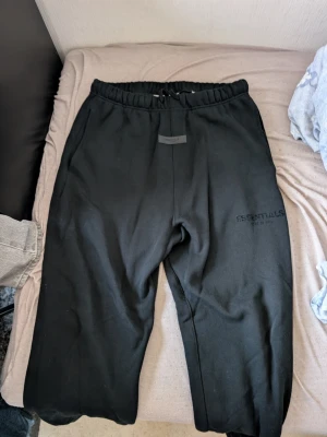 Svarta Essentials  FOGmjukisbyxor M - Säljer ett par svarta mjukisbyxor från Essentials i storlek M. Tillverkade i mjukt och skönt material, perfekta för chill dagar. Använda 2 gånger.