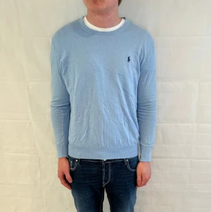 Polo Ralph Lauren Sweater Slim Fit Light Blue - Ljusblå stickad tröja från Polo Ralph Lauren i slim fit. Begagnad i mycket fint skick.