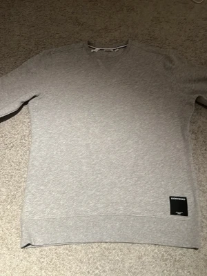 Grå sweatshirt från Björn Borg - Klassisk grå sweatshirt från Björn Borg med rund halsringning och ribbade muddar. Tröjan har en diskret svart patch med logga nertill och är tillverkad i mjukt bomullsmaterial. Perfekt för en avslappnad och stilren look.säljer för 450 kr kan möjligtvis gå med på priser ner till 250 kr!