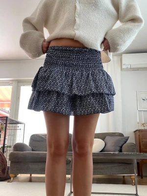 Minikjol - En jättesöt blåvit-mönstrad minikjol med volangdetaljer. Kjolen har även inbyggda shorts vilket är väldigt skönt. Från meet me there men säljs inte längre. 