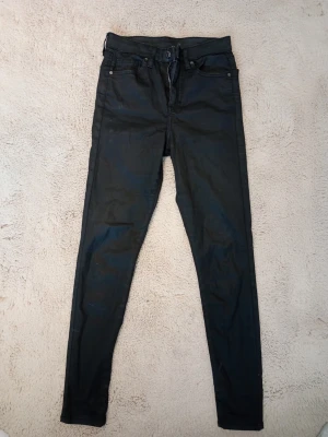 Svarta skinny jeans med hög midja - Säljer ett par svarta skinny jeans med hög midja och klassisk femficksmodell. Jeansen har smal passform hela vägen ner och stängs med knapp och dragkedja. Perfekta till en avslappnad eller trendig look.