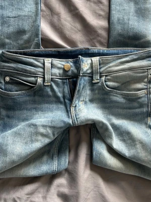 lågmidjade jeans - Säljer ett par ljusblå bootcut jeans med låg midja. Midjemått tvärsöver : 35cm Innerbensmått: 78cm. Pris kan diskuteras!! ❣️ säljs pga för små och är fåtals använd.
