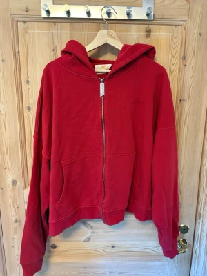 Trendt vision Röd zip hoodie med huva - Säljer en röd hoodie från Trendt vision med dragkedja och stor huva. Hoodien har två fickor framtill och ribbade muddar vid ärmar och nederkant. Perfekt för en avslappnad och chill stil. Materialet känns mjukt och bekvämt, 100% bomull i högkvalite. Aldrig använd endast testad.          Nypris 1100kr.