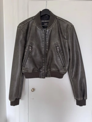Bomber skinnjacka, bomberjacka  - Snygg cropped skinnjacka med dragkedja framtill och två snedställda fickor med dragkedja. Jackan har ribbade muddar vid ärmslut och midja för en sportig look. Perfekt till allt. Från QTD LDN, strl 36. Ser exakt ut som skinnjackan från Zara. 