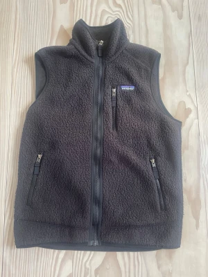 Svart fleeceväst från Patagonia - Säljer min svarta patagonia fleece väst då den blivit för liten. Riktigt snygg att ha inför hösten eller om man gillar att experimentera med lager på lager!