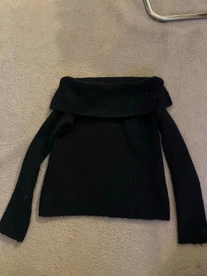 Mörkblå off shoulder stickad tröja - Snygg mörkblå stickad tröja med bred off shoulder-krage och långa ärmar. Tröjan har en mjuk och lite fluffig känsla, perfekt för att hålla värmen. Passar till både jeans och kjol för en trendig look. Tröjans storlek är 134/140 men den har en oversized passform och därmed sitter den perfekt på mig som i vanliga fall har 146/152, xs och xxs
