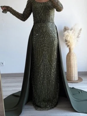 Mörkgrön glittrig långklänning Asya Dress - Säljer en elegant mörkgrön långklänning från Asya Dress med glittriga paljetter och långa ärmar. Klänningen har en figurnära passform, öppen rygg och ett långt släp för extra dramatik. Perfekt för dig som vill sticka ut på bal eller fest.