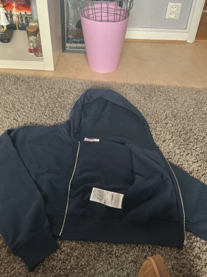 Mörkblå hoodie med dragkedja - En stilren mörkblå hoodie med dragkedja framtill och huva. Hoodien har långa ärmar och breda muddar vid ärmslut och nederkant. Perfekt för en avslappnad och cool look.