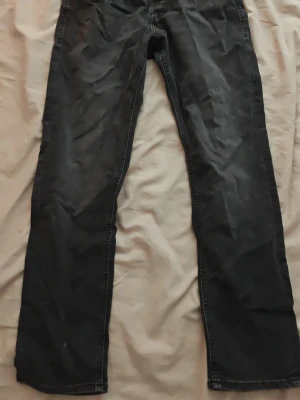 Mörkgrå jeans - Säljer ett par svarta jeans med rak passform och klassisk femficksdesign. Jeansen har normal midja och är sydda i ett slitstarkt denimtyg. Perfekta för dig som gillar en enkel och tidlös stil.