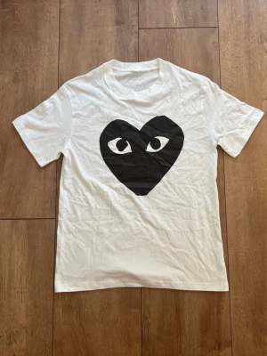 CDG Play T-shirt i vitt med svart hjärta 🤍🖤 (Strl S) - Säljer en skitsnygg och klassisk vit t-shirt från Comme des Garçons PLAY med det stora svarta ögon-hjärtat i storlek S. Använd sparsamt och i jättefint skick! Inget kvitto finns, men kika gärna på bilderna. Skriv ett DM om du vill ha mått eller funderar över något! ✨ 