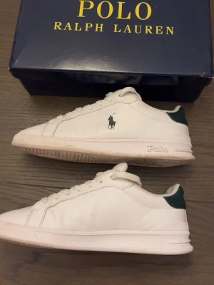Vita Polo Ralph Lauren sneakers - Snygga vita sneakers från Polo Ralph-Lauren, kommer i Ralph-Lauren kartong (inte orginal dock). Dessutom kommer de med ett par extra snören