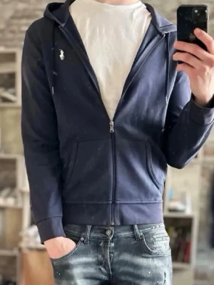 Polo Ralph Lauren  hoodie med dragkedja - Snygg mörkblå hoodie från Polo Ralph Lauren med dragkedja framtill och vit logga på bröstet. Klassisk huva med dragsko och två fickor fram. Perfekt till jeans för en avslappnad look.