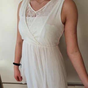 Vit klänning från VERO MODA - Söt sommrig klänning som aldrig riktigt kommit till användning. 100% polyester, och kommer från VERO MODA. Luftig och bekväm, slutar ungefär halvvägs ner på låren. Öppen i ryggen. Frakt betalas av köparen (48 kr)