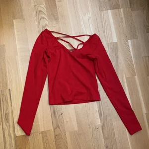 en röd tröja, storlek XS - en röd tröja med storlek XS. Ett V vid brösten sam bak fast den är öppen med trådar som mönster. Det ser ungefär ut som tre X men formade i V form. Använd 1/2 gånger för ca 3/4 år sen. Från Monki