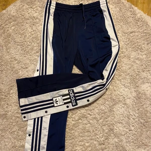 Adidas byxor - Säljer mina marinblåa Adidas byxor, knappt använda, de har knappar (funktionella) upp till rumpan och fickor med dragkedjor, de är lite stora i storlek för att vara 36 men har snören i midjan☺️ köparen står för frakten