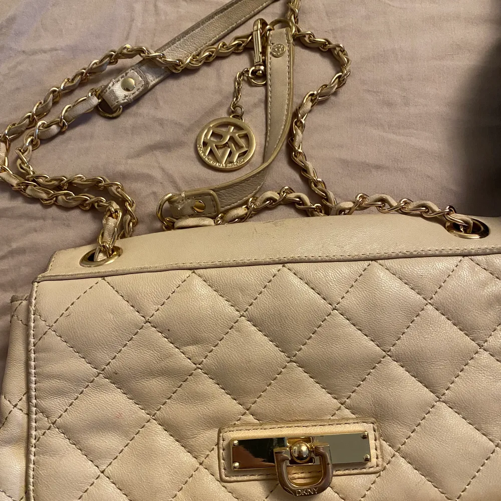 En beige/krämvit väska från DKNY. (Äkta) den har lite slitage på sig . Väskor.