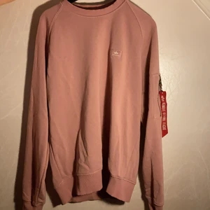 Alpha industries  - Säljer Alpha industries sweatshirt i ljusrosa. Flärpen på sidan är lite skadad som man kan se på bilden. Säljer tröjan för 200kr + frakt. Vid intresse så är det bara att skriva! 