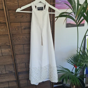 Vit halterneck-klänning - Vit halterneck klänning med stenar och paljetter, perfekt för studenten. Saknar två dekorationknappar på baksidan (de fyllde ingen funktion).