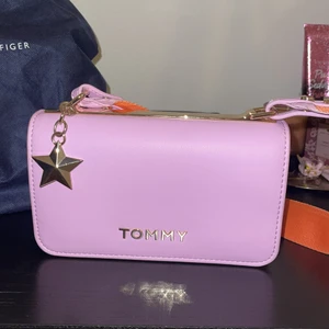 Hilfiger väska - Söt väska från Tommy Hilfiger. Dustbag kommer med väskan. Perfekt skick och inga skador, knappt använd. Axelbandet går att ha på båda hållen (ena sidan mer orange, andra sidan mer rosa). Pris går att diskuteras vid snabb affär!☺️