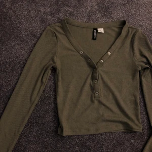 Topp med knappar - Tajt och lite kortare topp i ribbat material. Väldigt stretchig. Går att knäppa upp knapparna om man vill ha mer urringat