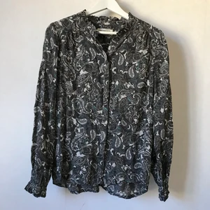 Grå mönstrad blus i silke - Härlig skjorta eller blus från Rosenunde i djup grå med mönster. Vackra veckade detaljer vid krage, rygg och ärmslut. I en luftig och skir silkesblandning. Märkt 38 men funkar för både XS, S och M skulle jag säga.   Kan mötas i Stockholm eller skicka mot fraktkostnad! ✨🌸✨