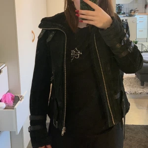 Jofama bikerjacka i skinn - Fin varm svart jofama by kenza bikerjacka. I skinn/mocka material. I fint skick. På en av armarna har en detailj till remmarna lossnat men kan sys på enkelt igen.  Storlek 38, hade passat 36 med. 