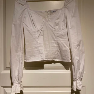 NA-KD TOPP - En vit topp från NA-KD, inbyggd bygel och volang löst ner på ärmen