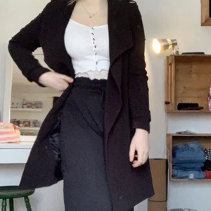 Kappa / trenchcoat strl 34 - Super fin svart kappa / trenchcoat strl 34, finns så de går att knyta i midjan, ser ut som ny, mellan kort modell, fint knäppe i armarna, köparen står för frakten