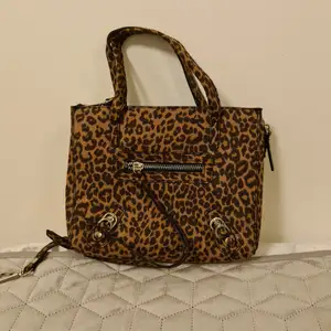 Leopardmönstrad väska där man kan öppna dragkedjor på sidan och göra den lite större. 
