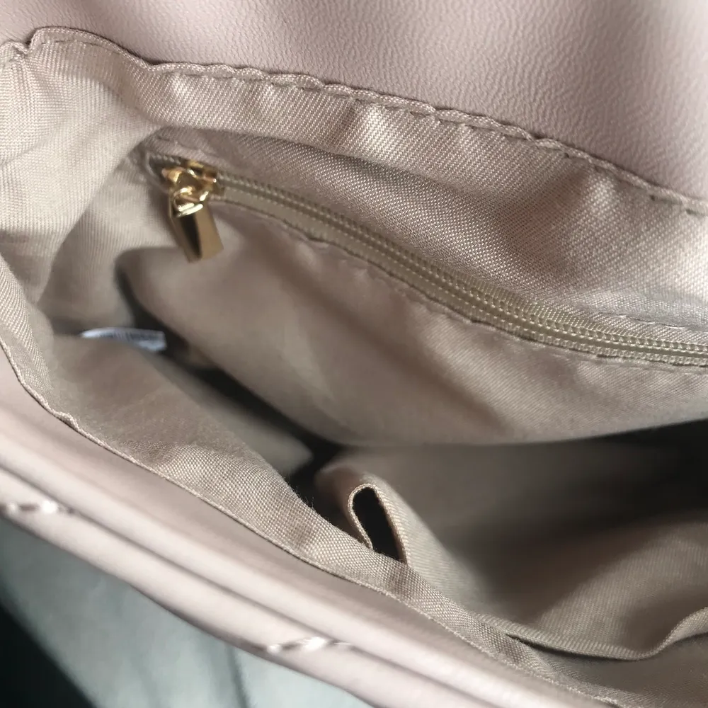 Handväska med axelrem delvis i kedja. Färgen är beige/rosa. Två innerfickor, en till mobil och en med dragkedja. Gratis frakt! . Väskor.