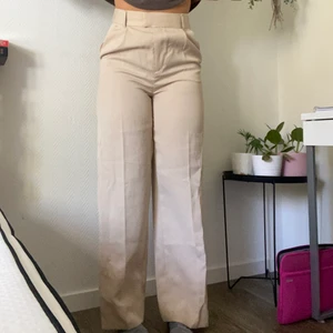 Beiga kostymbyxor - Ett par beiga oanvända kostymbyxor i en vid och längre modell. Passar perfekt för er längre personer, som preferens är jag 174 cm och det når ner till golvet för mig. Passar perfekt till alla tillfällen och är fina till det mesta! Tyvärr känner jag att jag inte passar i ljusare byxor därför säljer jag, prislapp är kvar. Nypris: 249kr 