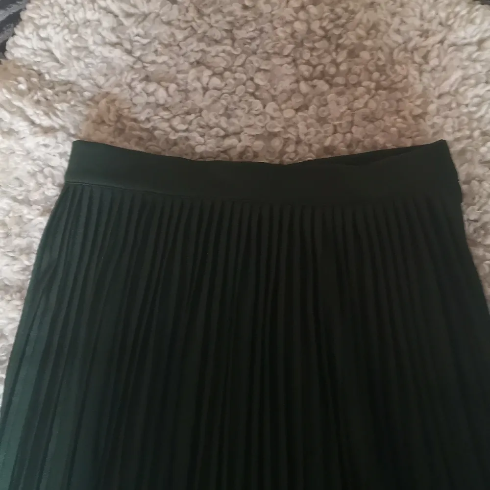 Grön plisserad kjol med fin passform och fall. Dragkedja och knappar på sidan. Fint skick! . Kjolar.