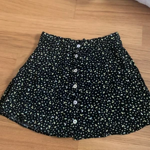 Kjol  - Säljer en svart kjol från hm med små gula och vita blommor💖💖 Den är i storlek 38 men jag skulle säga att de är en 34/36 då den absolut inte sitter som 38 utan den är mindre.🥰