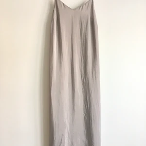 Weekday Cupro Dress - Grå klänning från weekday. Rak i modellen med smala band och en slits baktill.   Storlek XS.   66% cupro  34% polyester.  Innertyg 100% polyester.   Sömmen har släppt lite på ena bandet, lätt fixat med en liten söm. Se bild.   Aldrig använd.   150kr